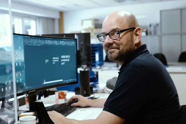 Ein Mann sitzt am Computer und schaut in die Kamera